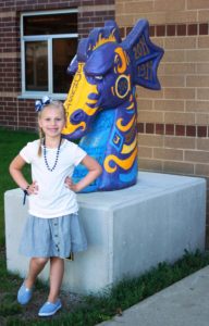A girl standing in front of a Johnston Dragon statue