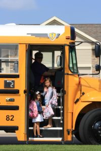 Young girls getting on a Johnston bus and waving to the camera