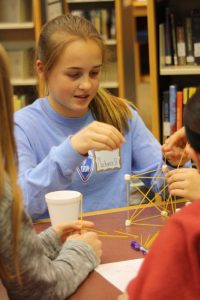 Middle School female works on a STEM project with classmates.