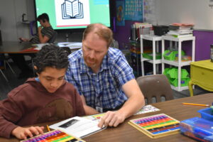Associate works with student in the classroom