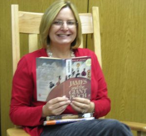 Mrs. Tegels sitting in a wooden chair reading James and the Giant Peach.