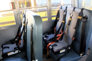 Photo of bus seats equipped with harnesses and seat belts.