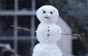 Image of a snowman outside on a snowy day. 