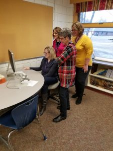Teachers work together to learn the new digital checkout system at YHMA library.