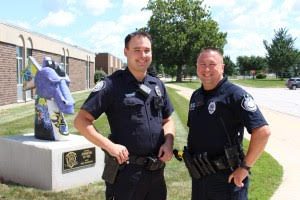 The two Officers, Zach Grandon and James Slack, stand in front of the Johnston High School.