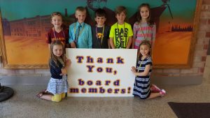 Lawson students gather around a "Thank you board Members" sign for school board appreciation month. 