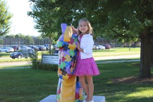 A Wallace students posees by the JOhnston Dragon statue on the first day of school.