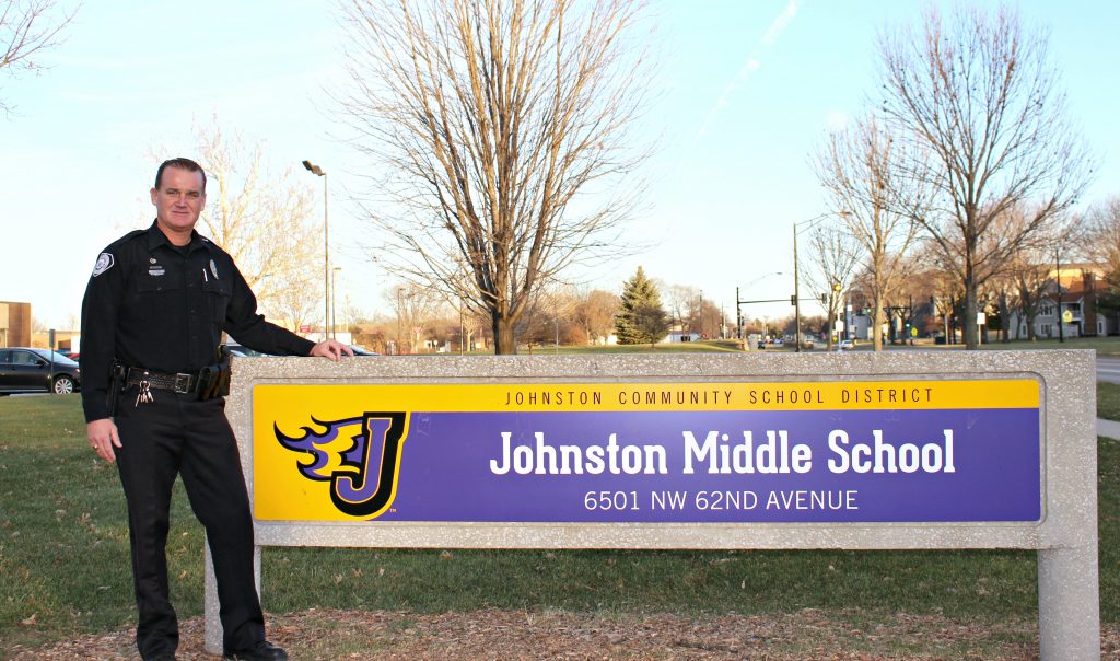  Officer Bryan Townes stands next to the JOhnston Middle School sign