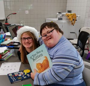 Two Johnston high School students smile after opening a present and receiving a new book. 