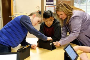 Summit students and their teacher, Shannon DaRos-Hall, work together to solve an problem on their iPads.