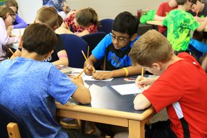 Fifth grade boys complete a creative writing prompt during a workshop.