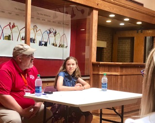JMS ninth grader Anna Larson, right, speaks to Living History Farms attendees about her historical paper, "Milk Wars." Also pictured is Dan Jones, LHF Educational Director.
