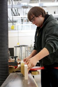 JHS student cuts wood in the wood shop