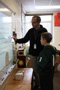 Beaver Creek fifth grade teacher Dan Loy explains a concept to one of his students during their arcade game unit. 