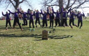 11 young women jump behind their trophy